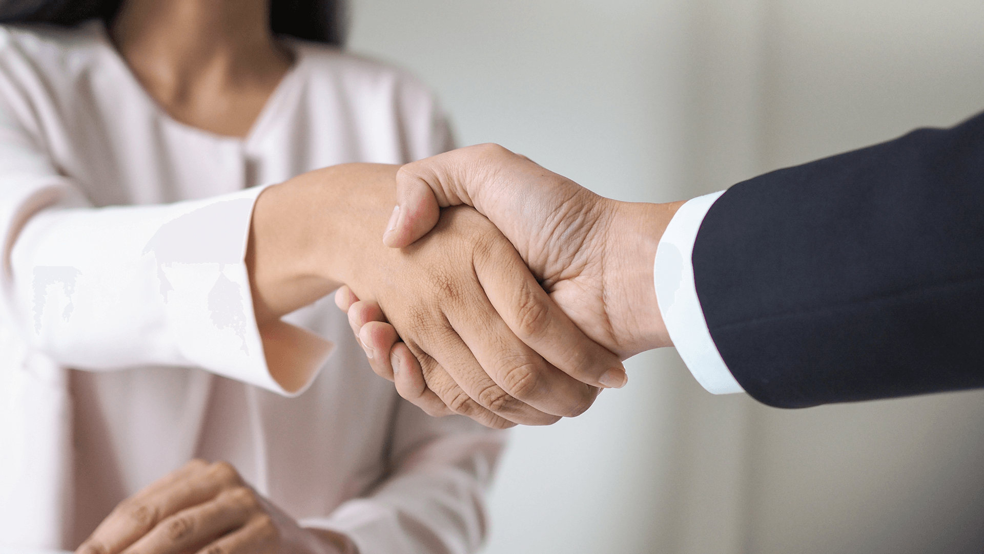 A professional handshake between two individuals, signaling a formal agreement or introduction.
