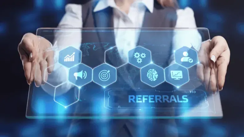 A professional interacting with a futuristic holographic interface displaying various business-related icons and a highlighted section labeled "referrals.