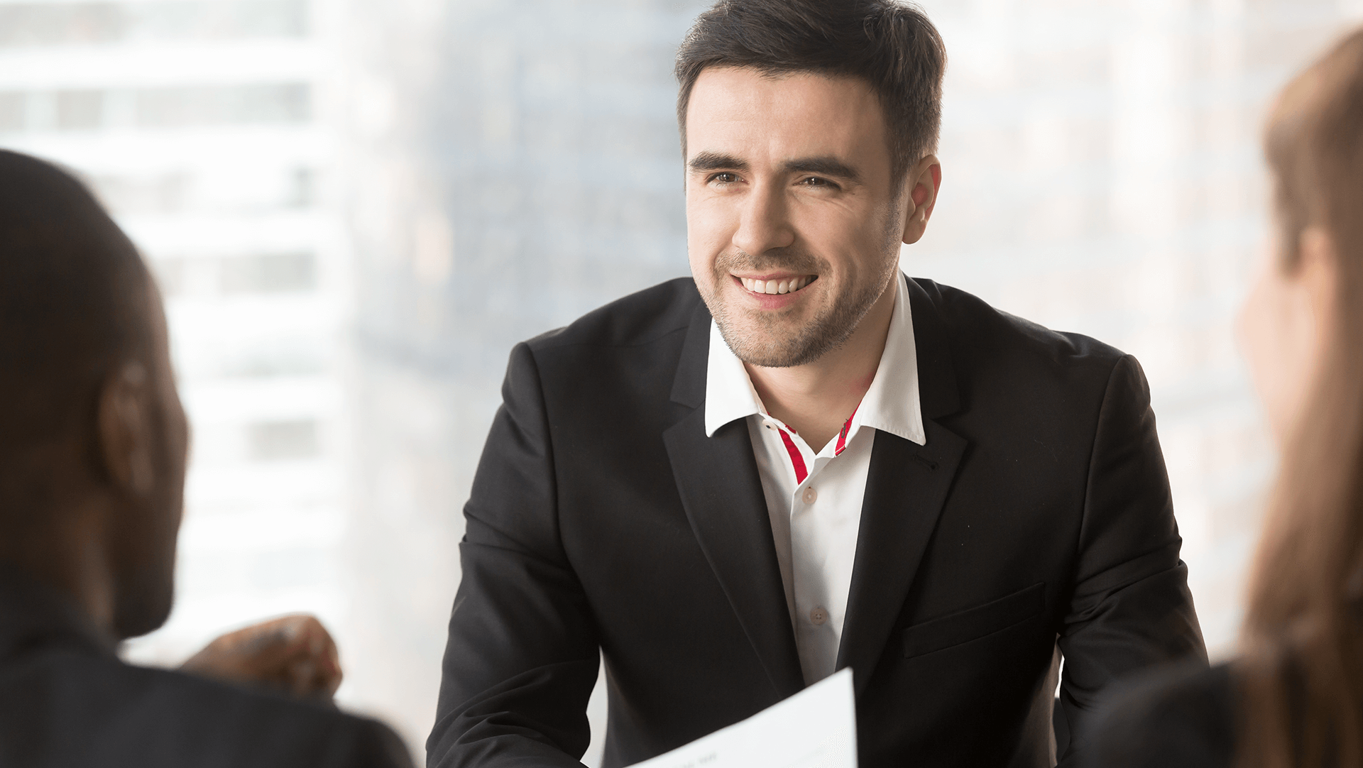 Smiling businessman in a meeting with colleagues, exuding confidence and engagement.