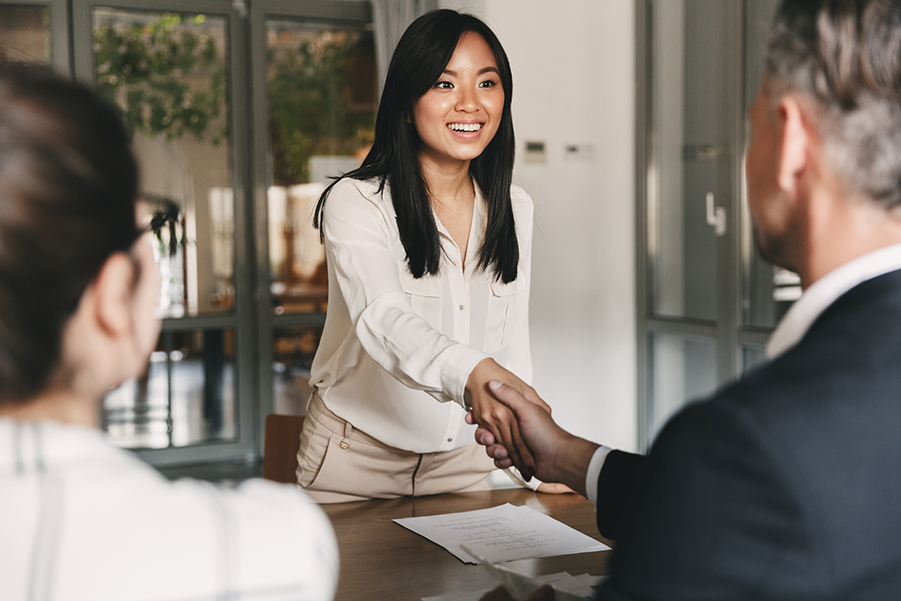 Businesswoman confidently shaking hands during a meeting, signaling a successful agreement or introduction.