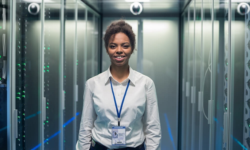 Smiling female IT worker standing beside server racks