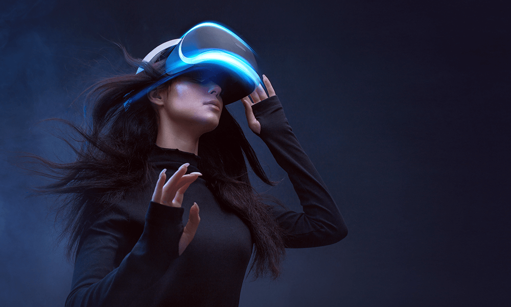 A woman immersed in a virtual reality experience, with her hair flowing as she is surrounded by a cool, dark ambiance.